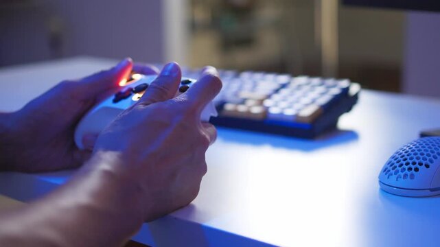 Adult man reacting with game controller during intense gameplay at glowing PC desk, side view with colorful RGB light reflections and focused expression