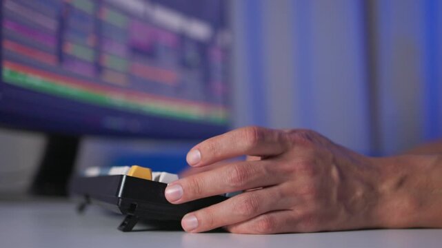 Close-up of adult hand pressing keypad on card payment terminal while inserting plastic card at office desk under cool blue lighting with blurred computer monitors in background