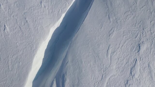 Aerial Top-Down View of Deep Blue Glacier Crevasse in Snowfield