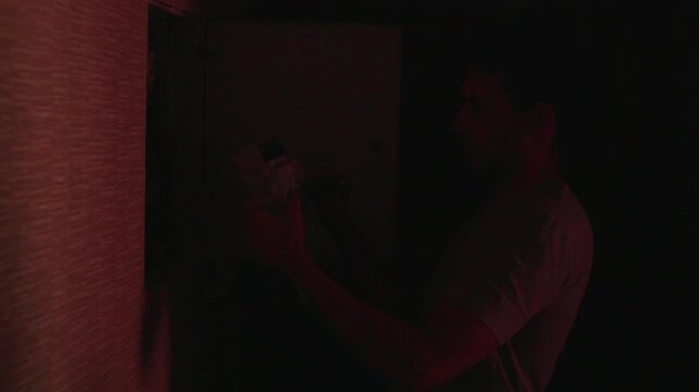 Technician removing lower circuit breaker module from open residential electrical panel, inspecting internal wiring and meter display during home safety service
