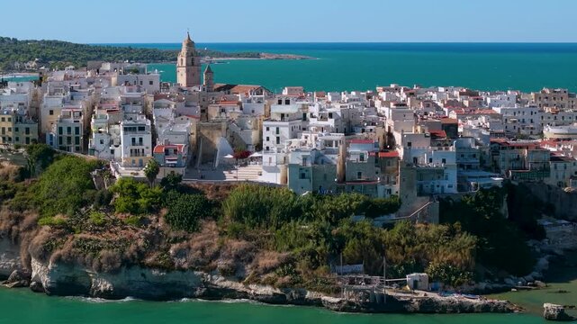 Vieste white town on rocky cliff peninsula Gargano Puglia Italy 70mm telephoto drone view from Adriatic Sea showing historic coastal village on promontory cinematic B-roll