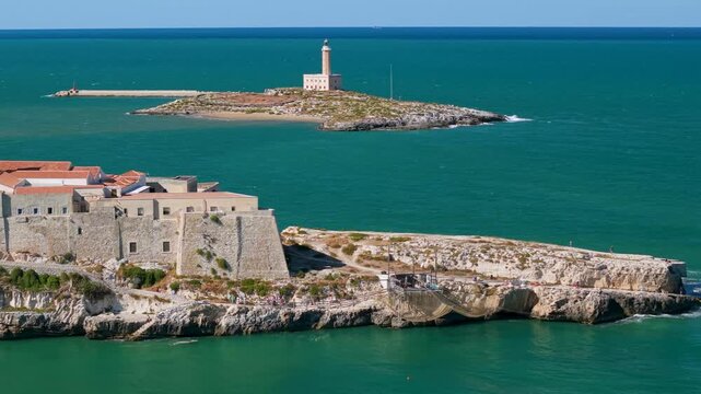 Vieste Gargano Puglia Italy 4K drone video. 70mm telephoto reveal of San Francesco church and Sant Eufemia island lighthouse. Adriatic Sea cinematic B-roll