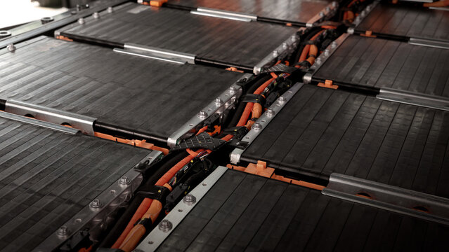EV car service. Electric vehicle battery pack being serviced or inspected in automotive workshop. Large battery modules and high voltage components. Modern EV power systems. Lithium ion NMC NCA or LFP