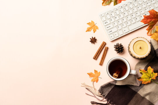 Autumn office desk. Laptop, cup of tea, spices and scarf with fallen leaves. Flat lay with space for text.