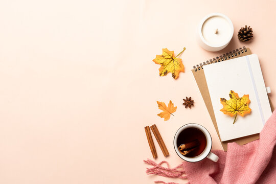 Autumn flat lay background. Autumn leaves, notepad, scarf and leaves on yellow background.