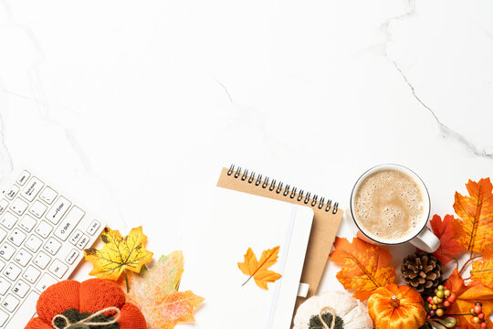 Autumn office desk. Laptop, notebook, coffee cup and scarf with yellow leaves. Flat lay with space for text.