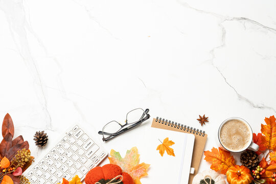 Autumn office desk. Laptop, notebook, cup of coffee and yellow leaves with pumpkins. Flat lay with space for text.