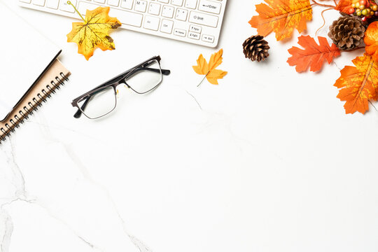 Autumn office desk. Laptop, notebook, hot tea and scarf with yellow leaves. Flat lay with space for text.
