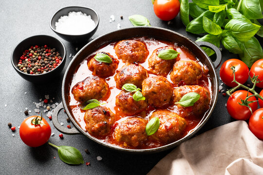 Meatballs in tomato sauce with ingredients for cooking. Traditional italian recipe.