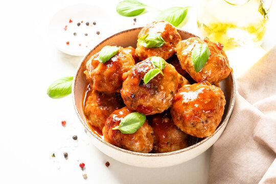Meatballs in tomato sauce and basil on white kitchen table. Traditional recipe.