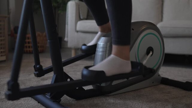 Woman's legs exercising on elliptical machine at home