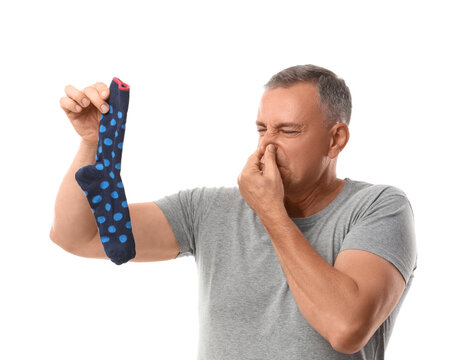 Bad odor and hygiene, man holding a smelly dirty sock and pinching his nose in disgust, personal freshness and laundry problems on white background