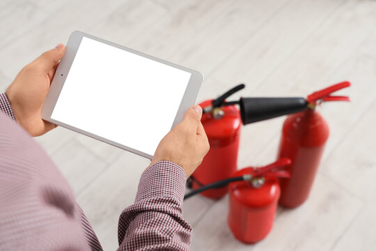 Fire safety inspection and risk management, person holding tablet with blank screen near red fire extinguishers for maintenance and compliance check