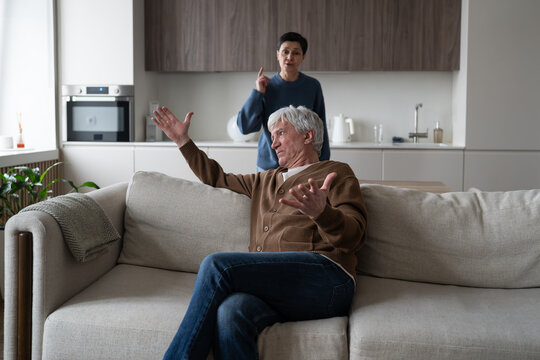 Senior family brawl and emotional breakdown, elderly couple in serious argument and disagreement, frustrated angry wife accusing irritated displeased husband on sofa, hopelessness and marriage dispute