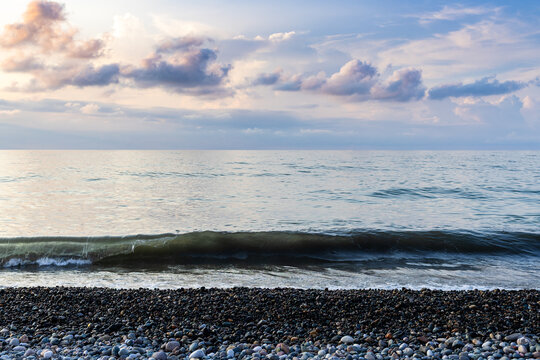view of wave sea water from pebble beach at sunset