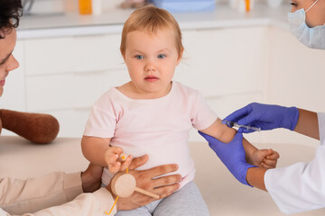 Fototapeta premium Child vaccination and pediatric healthcare, doctor giving an injection to a toddler with father holding a toy in a medical clinic examination room