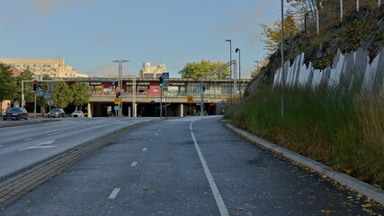Fototapeta premium Separated bicycle route leading toward a railway station area with traffic lights, rail infrastructure and urban buildings in Finland.