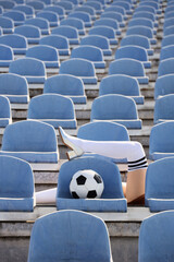 Obraz premium Sports fashion and femininity, woman legs in high heels and soccer socks with ball in empty stadium seats for creative advertising and lifestyle