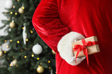 Obraz premium Christmas surprise and holiday gift giving, Santa Claus hiding a present behind his back near a decorated tree for festive celebration and winter joy