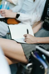 Closeup Of Woman in Short Skirt Writing Notes In Notebook During Business Meeting © vladdeep