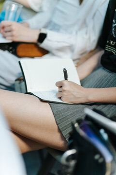 Closeup Of Woman in Short Skirt Writing Notes In Notebook During Business Meeting