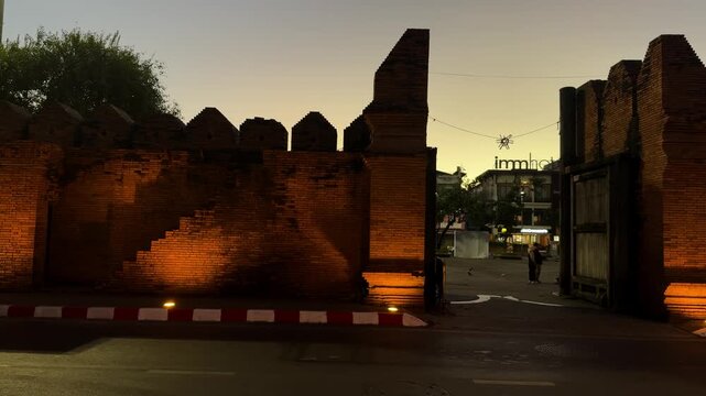 Illuminated brick wall and entrance of Tha Phae Gate at dusk in Chiang Mai