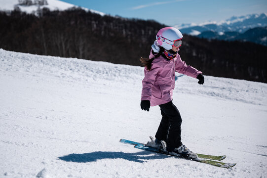 Little girl learning skiing on a sunny mountain slope