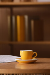 Morning routine and coffee break, yellow espresso cup on a wooden table with a newspaper in a cozy home office or library setting © Pixel-Shot