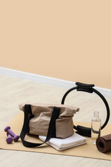 Fitness and wellness routine, gym bag with pilates ring and dumbbells on yoga mat for healthy...