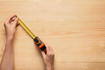 Fototapeta premium Home improvement and renovation planning, hands holding a measuring tape on a wooden table for construction project measurement and interior design
