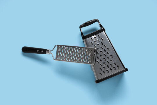 Food preparation and cooking tools, stainless steel box grater and handheld zester for culinary tasks and kitchen equipment on a blue background