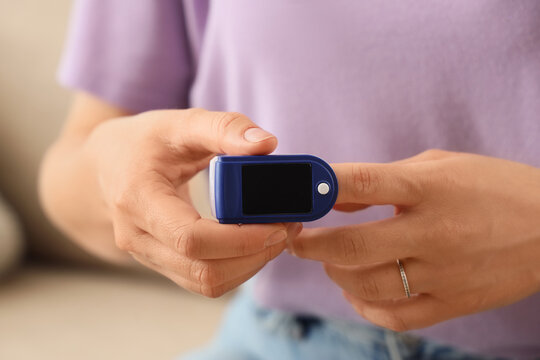 Telemedicine and health monitoring, person using a pulse oximeter to check blood oxygen saturation and heart rate at home for wellness and medical care