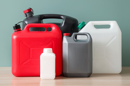 Industrial chemical storage and supply chain logistics, plastic jerrycans and containers for hazardous materials and liquid fuel on a wooden table