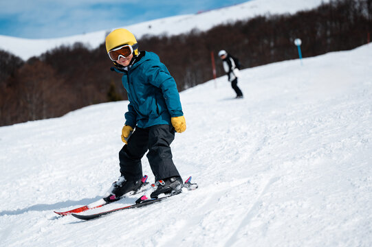 Young child learning skiing on snowy mountain slope