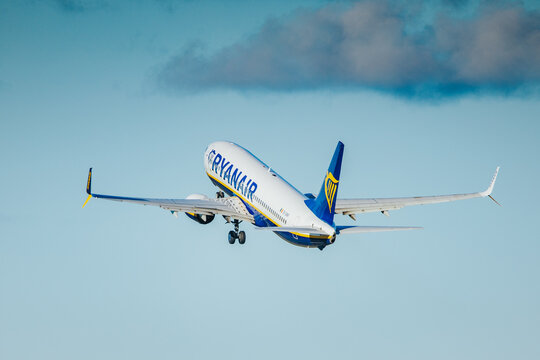 Riga, Latvia - September 27, 2026: Ryanair passenger airplane flying beneath blue clouds with landing gear extended and winglets visible in an open sky aviation photograph