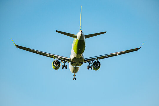Riga, Latvia - September 27, 2026: Commercial passenger airplane approaching runway with landing gear and engines visible against clear blue sky, photographed from below as an aircraft in flight