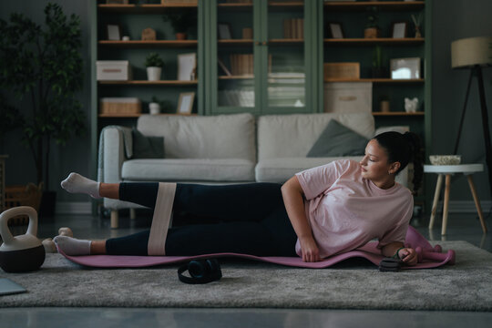 Woman exercising leg with resistance band at home