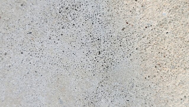 Close-up view of a rough gray concrete surface with granular texture and small pitted holes, industrial construction background