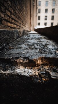Weathered stone ledge and aged brick wall in an urban alleyway with a blurred building facade in the background on a moody day