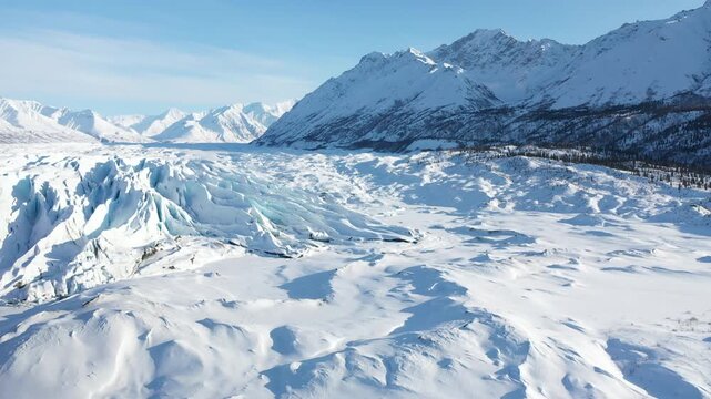 Panoramic View of Sunlit Glacier Snowfield Below Polar Mountain Range