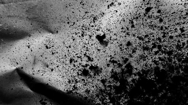 Abstract black and white texture with scattered ink splatters and grainy particles creating a distressed grunge effect on a textured surface