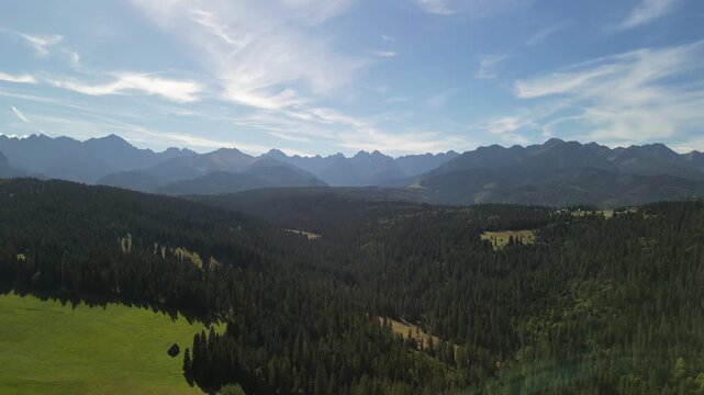 Bukowina Tatrzańska - Polska
Piękny widok na Tatry Wysokie nagrany dronem w słoneczny dzień. G&oacute;ry, chmury, słońce, pola, droga g&oacute;rska, las, Podhale.