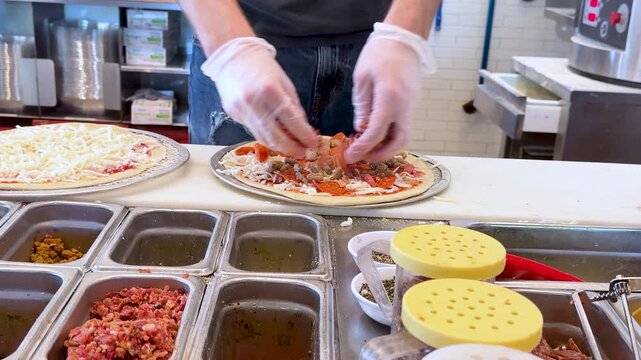 Chef Adding Fresh Toppings on Pizza in Commercial Kitchen