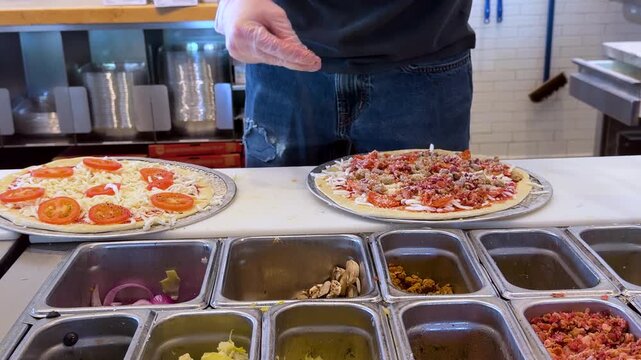 Chef Adding Fresh Toppings on Pizza in Commercial Kitchen