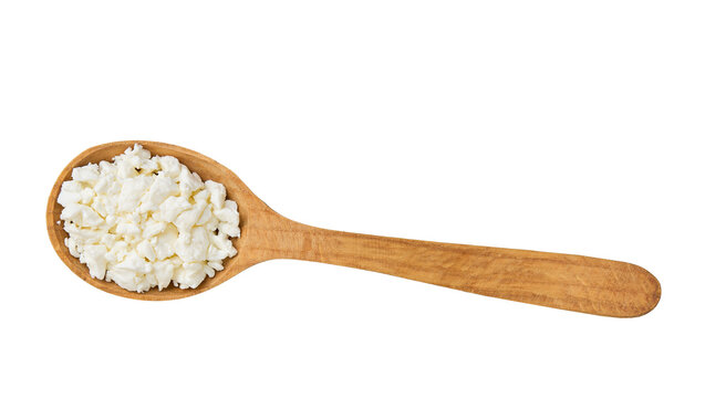 Fresh cottage cheese in a wooden spoon isolated on a white background, top view.