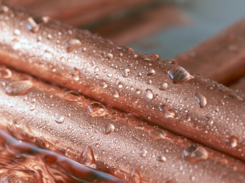 Close-up of polished copper pipes covered in dew droplets with water droplets metallic texture industrial metal condensed water plumbing materials copper material metal surface brown texture