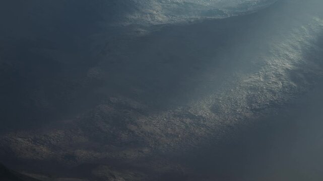 A wide view shows clouds filling the sky above the land during daylight. The clouds appear thick and cover much of the blue sky. Sunlight shines through in some areas.
