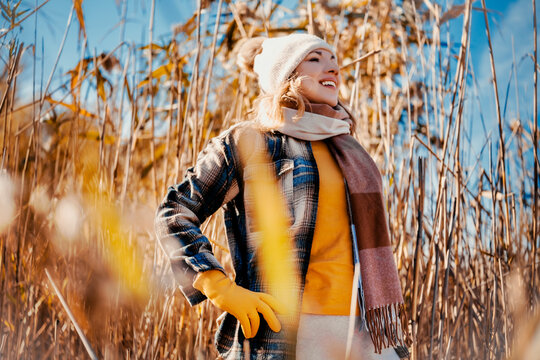 Happy woman walking through autumn reeds in park &mdash; pure nature harmony. Cheerful hiker exploring tall sunny grass. Joyful outdoor recreation promoting excellent psychological recovery.
