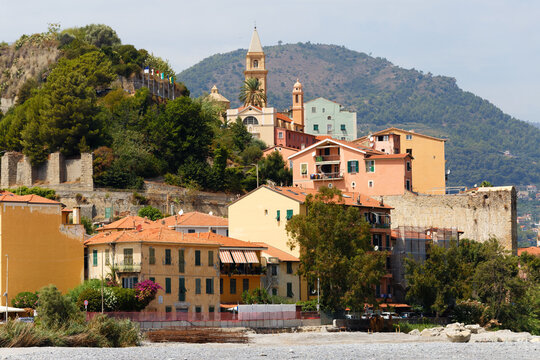 Ventimiglia hillside old town with bell tower, colorful houses and ancient walls seen from a pebble beach, Liguria, Italy