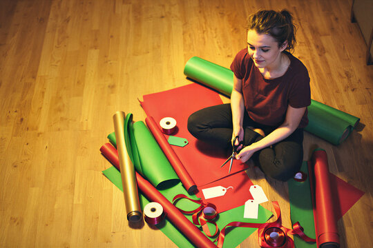 Woman wrapping Christmas gifts on the floor at home